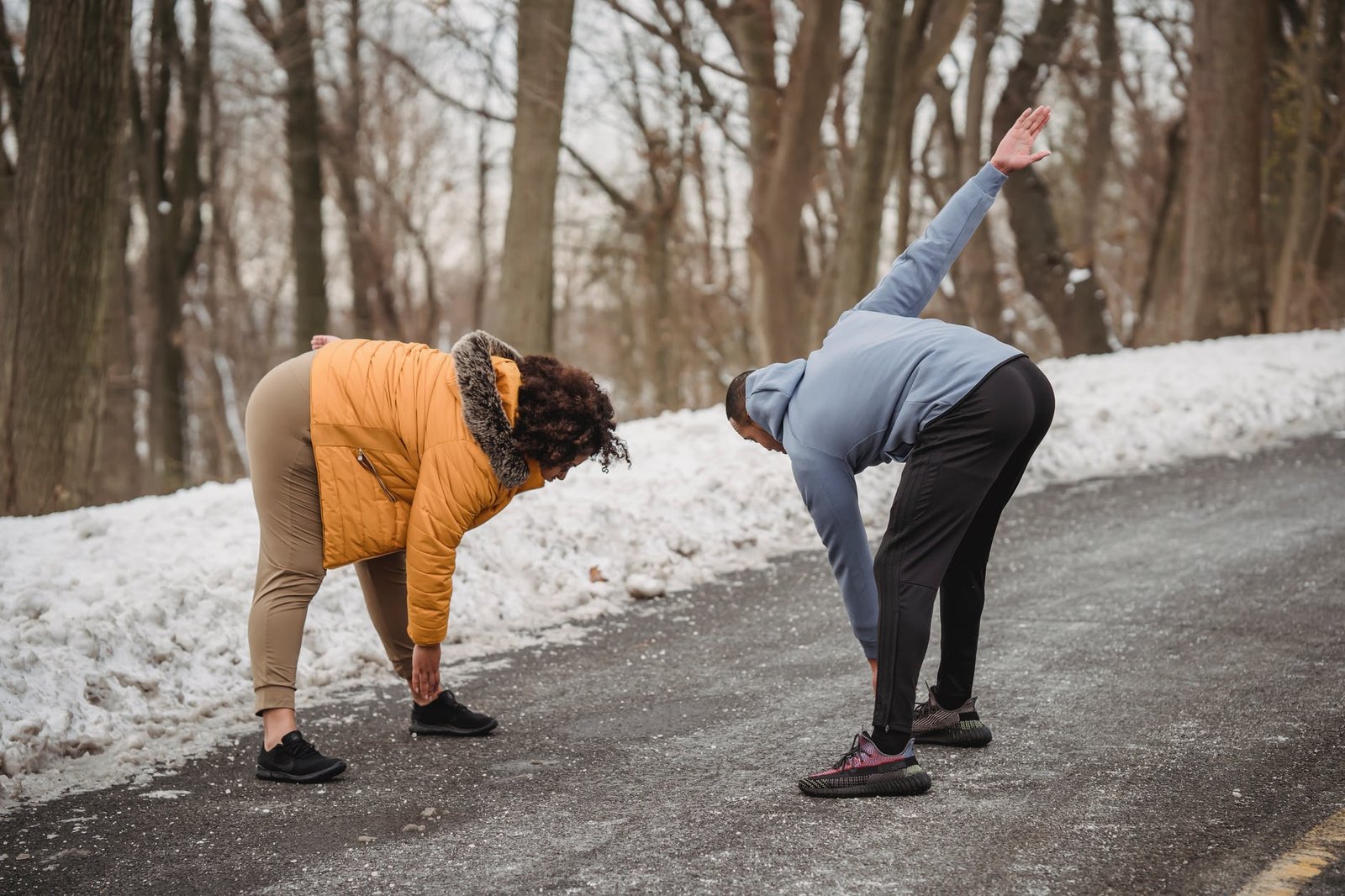unrecognizable black couple stretching in snowy park